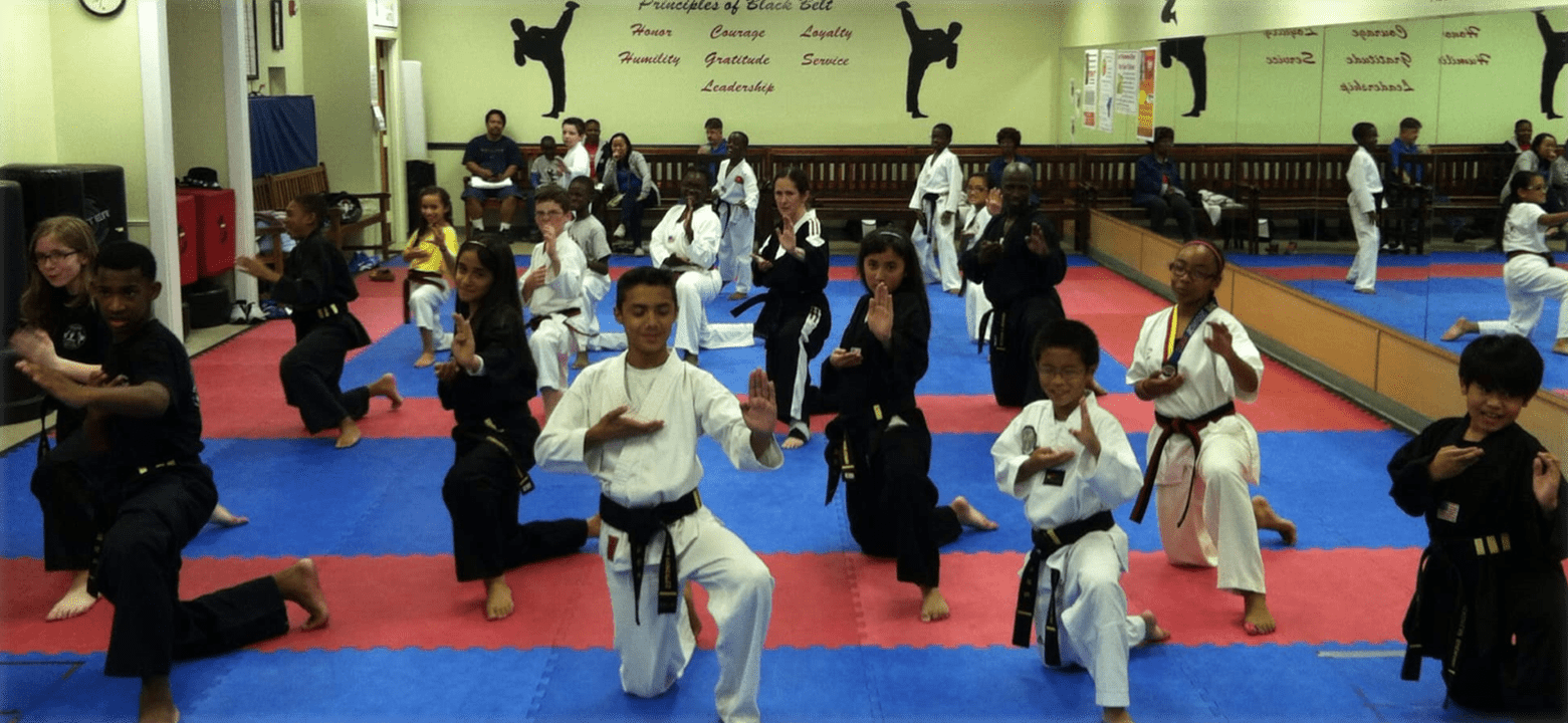 Group of martial arts students practicing coordinated exercises together inside a dojo-style training environment.