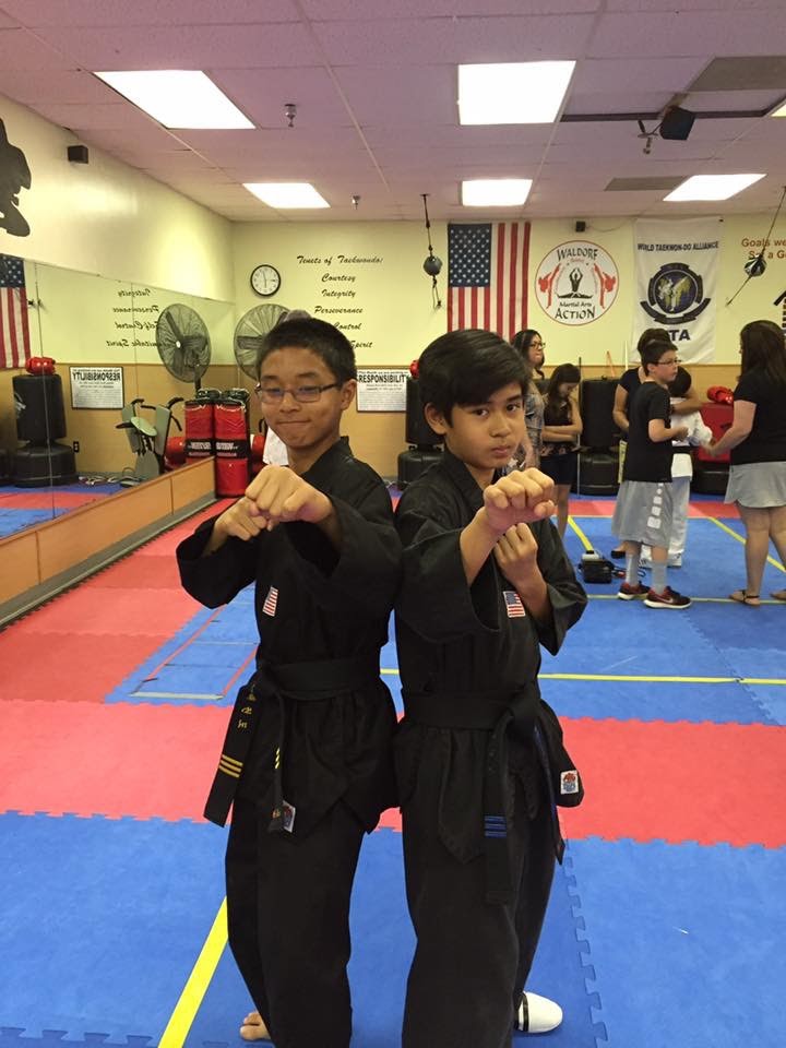 Martial arts students seated on mats participate in a structured class activity within the training space.