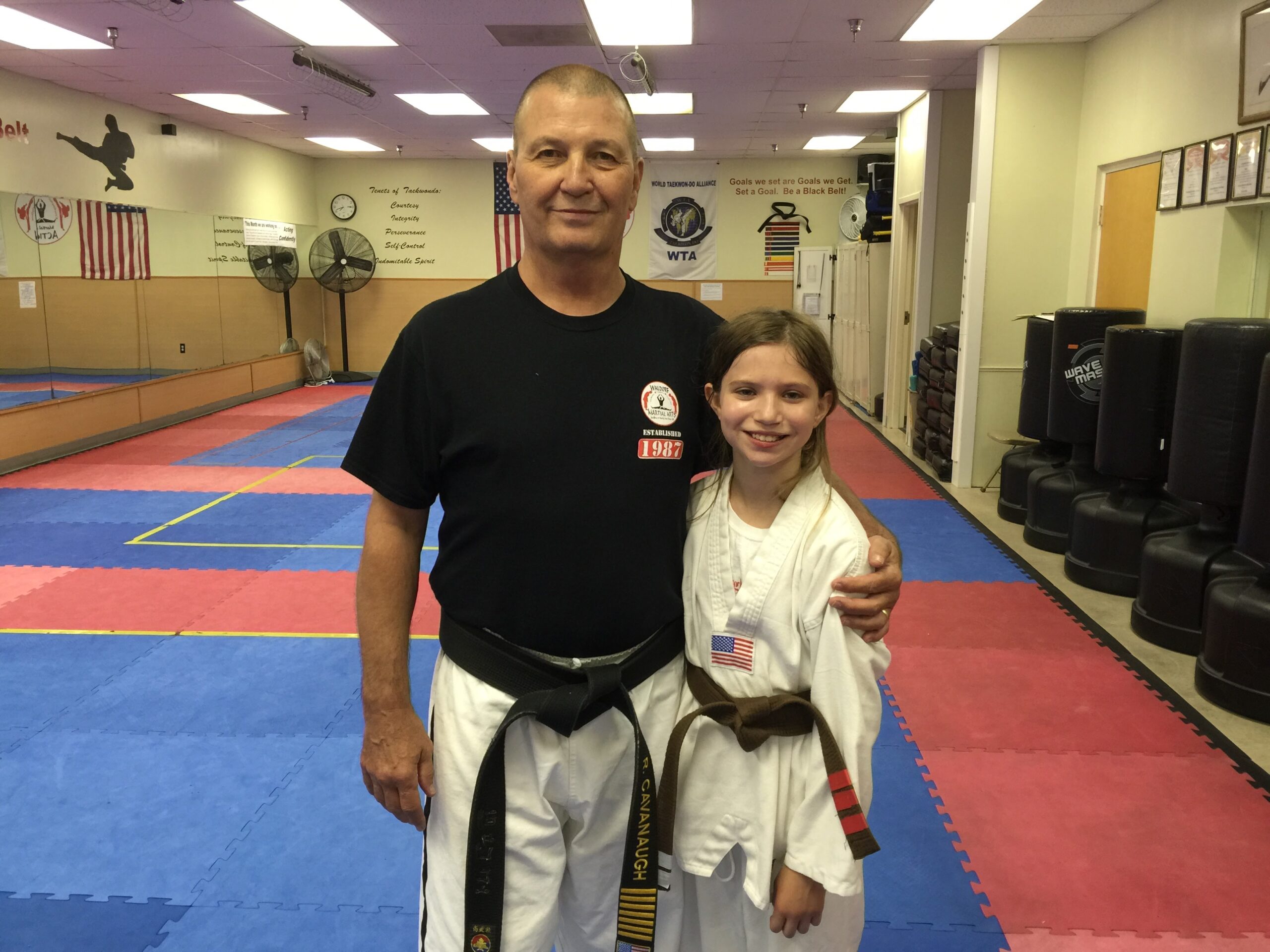 Martial arts students seated on mats participate in a structured class activity within the training space.