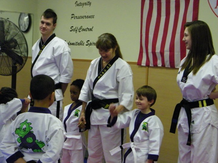 Martial arts instructor observes students lined up in uniform during an in‑class lesson.