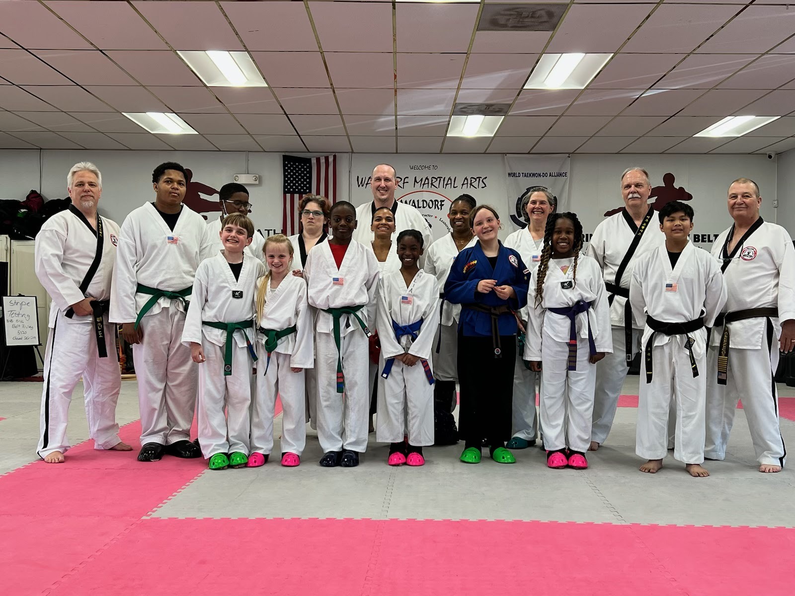 Martial arts students seated on mats participate in a structured class activity within the training space.